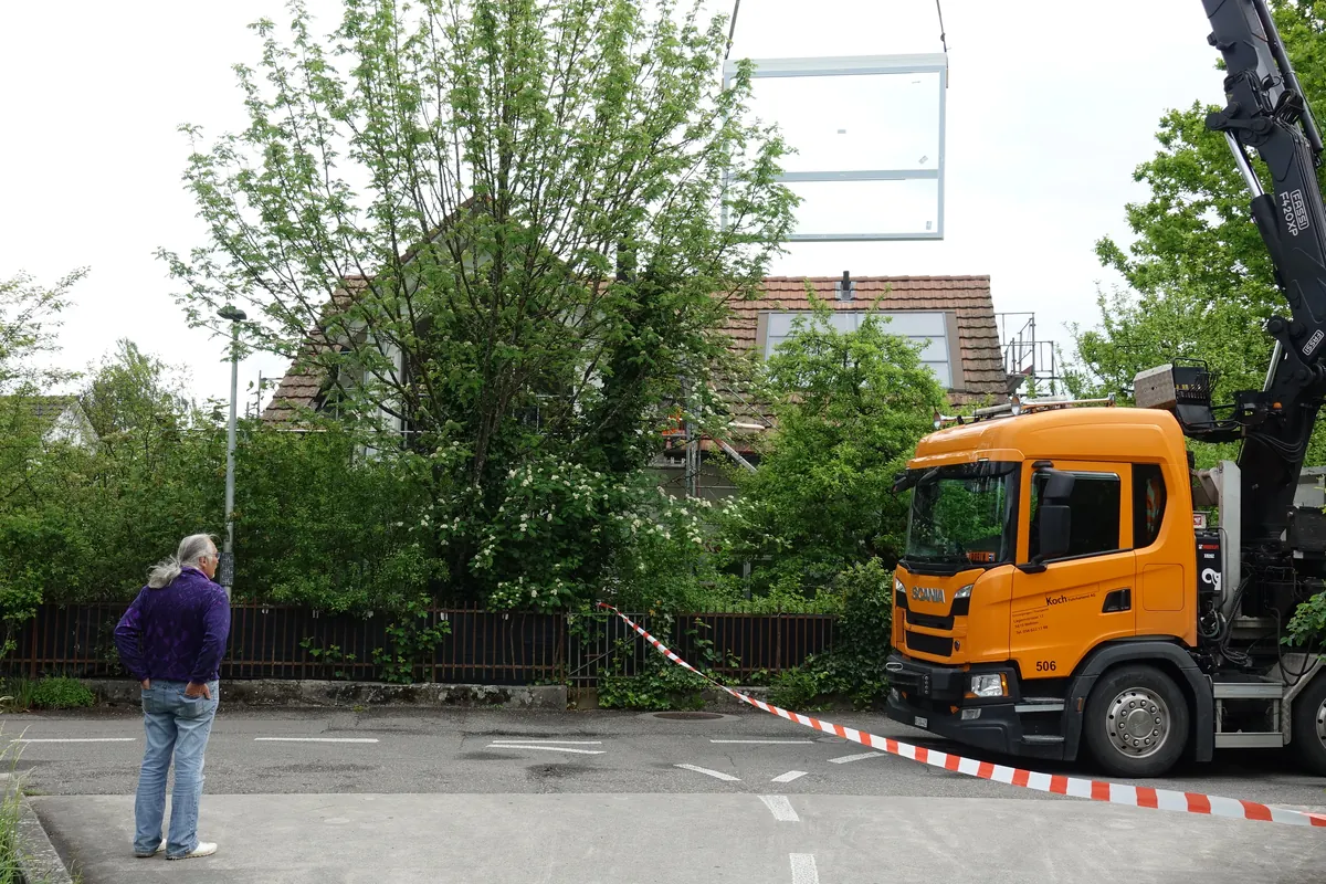 Kranwagen vor dem Objekt, ein Fensterelement hängt am Ausleger